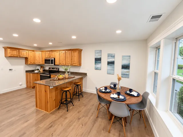Kitchen with wood-finish flooring, recessed lighting, wood cabinetry, and a central island with a stone-finish countertop