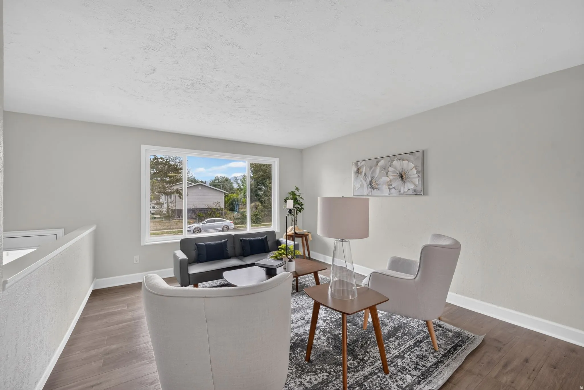 Spacious room featuring wood-finish flooring, a large multi-pane window, and light-colored walls