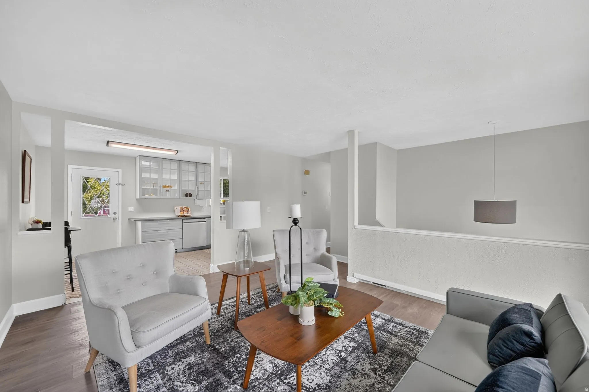 Living area featuring wood-finish flooring, light grey wall tones, and a suspended drum pendant light