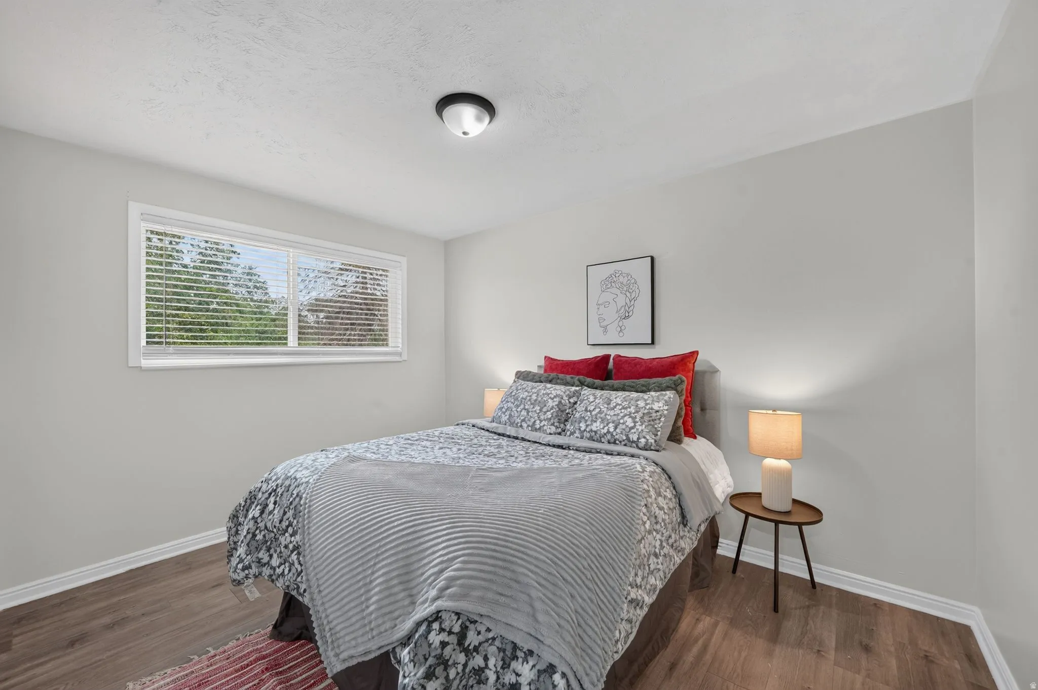 Wood-finish flooring, white walls, and a large window with blinds