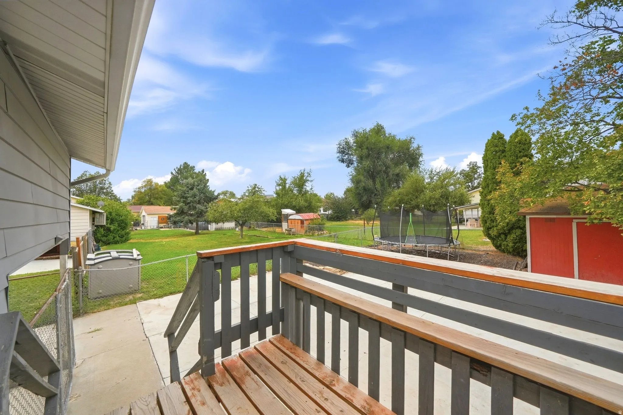 Rear exterior featuring siding, a wood-finish deck with railings, and a concrete patio