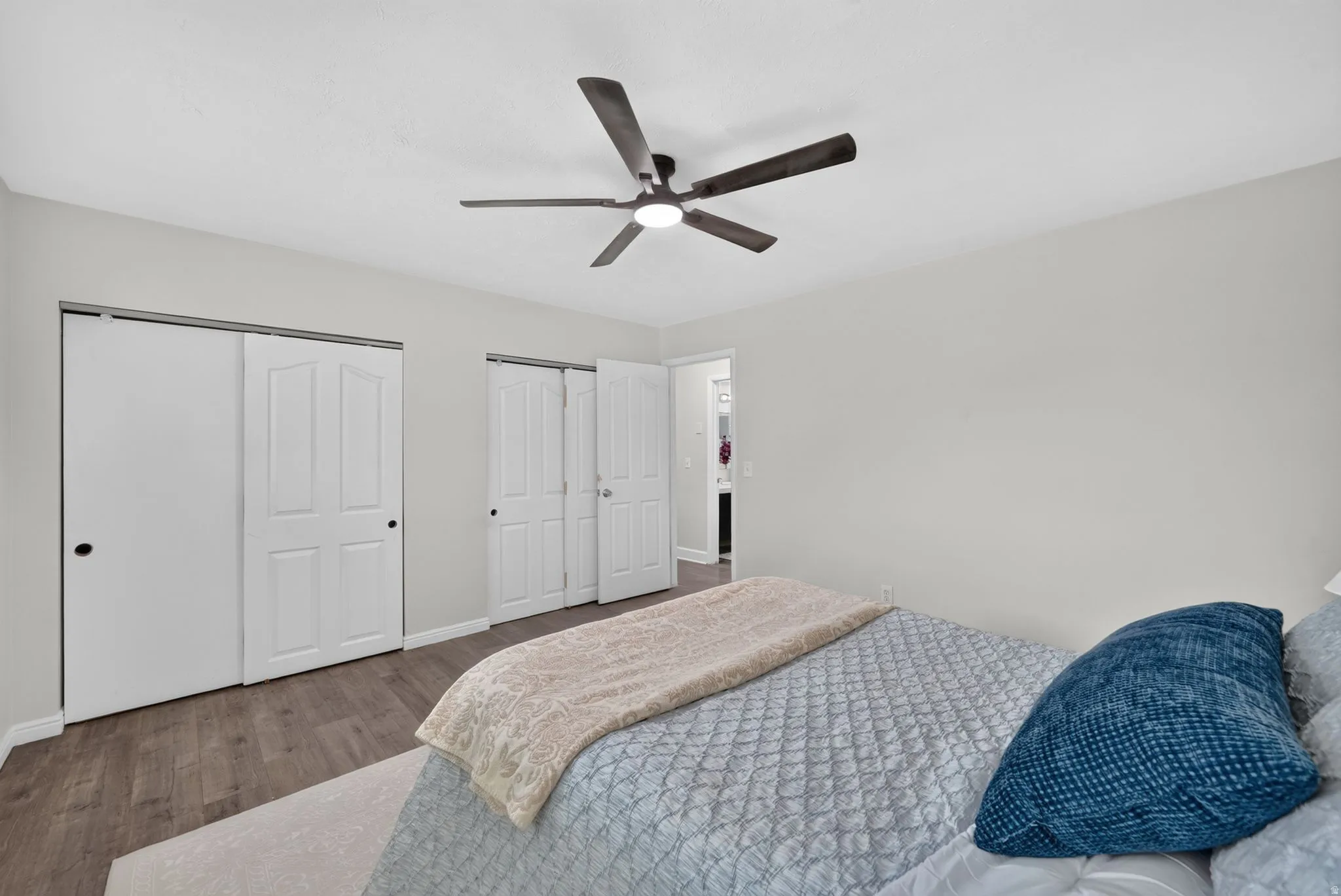 Ceiling fan with integrated lighting, wood-finish flooring, and white paneled sliding closet doors