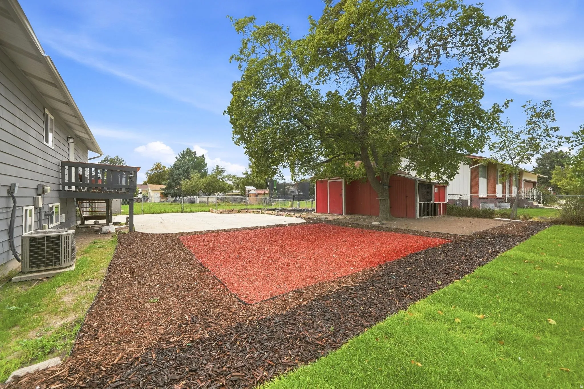 Expansive backyard featuring a manicured lawn, dedicated patio space, and mature trees