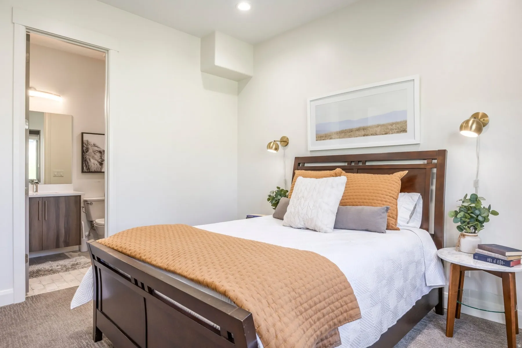 Recessed ceiling lighting, wall-mounted sconces, light gray carpeting, and an ensuite bathroom featuring a vanity with wood-finish cabinetry
