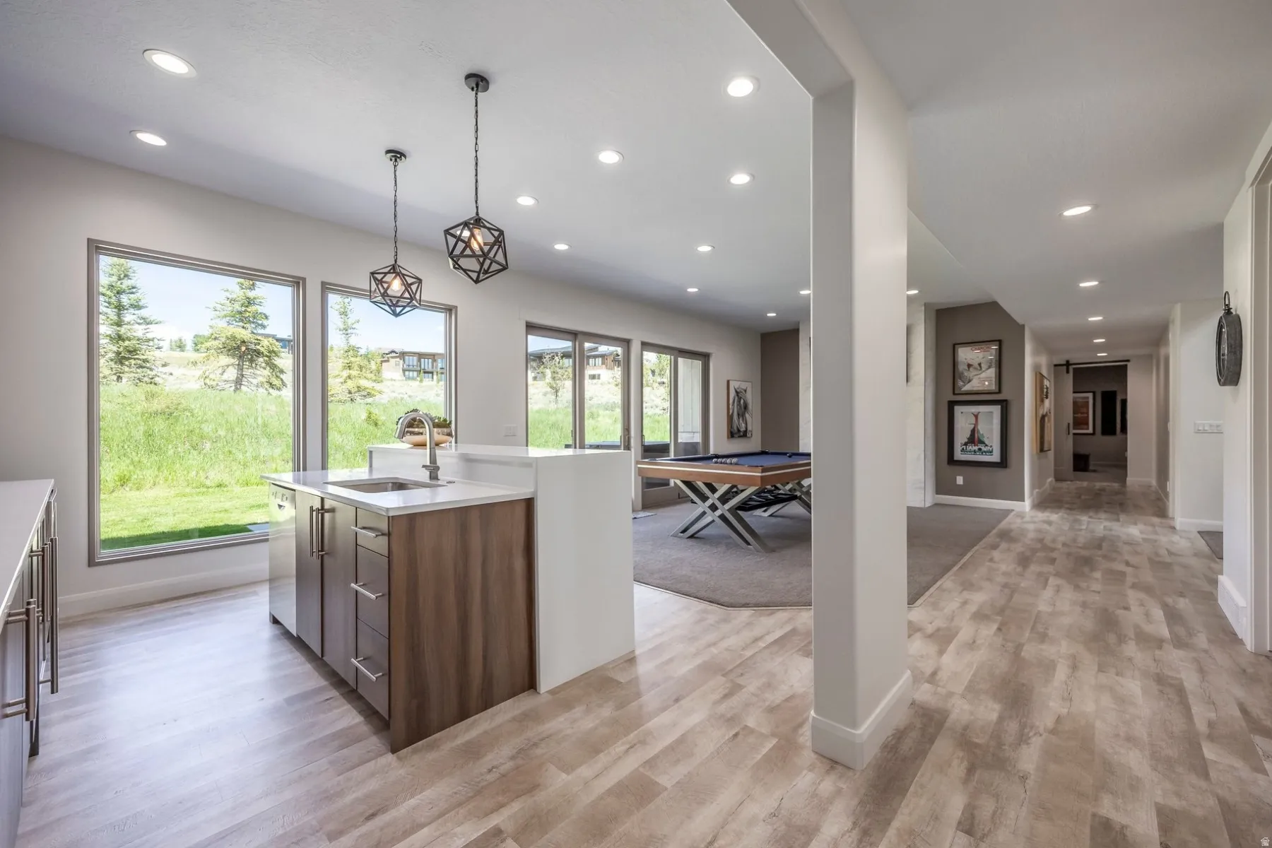 Wood-finish flooring throughout, recessed lighting, and a wet bar with a stainless steel sink