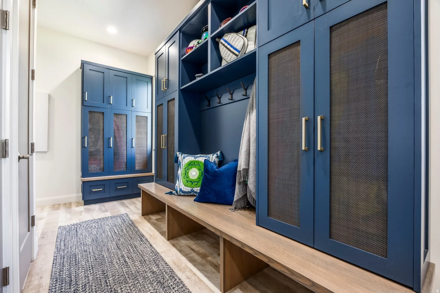 Built-in navy cabinetry with mesh-front doors, open shelving, and a wood-finish bench