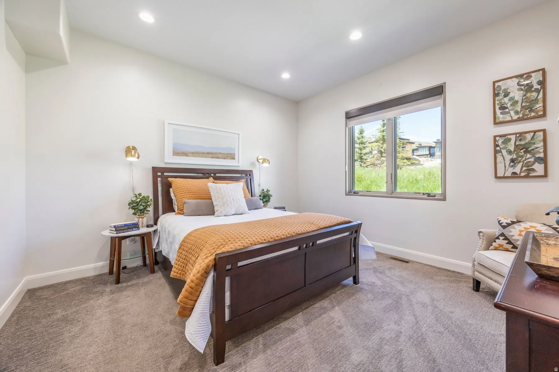 Recessed ceiling lighting, a large window with natural light, wall-mounted sconce lighting, and soft grey carpeting