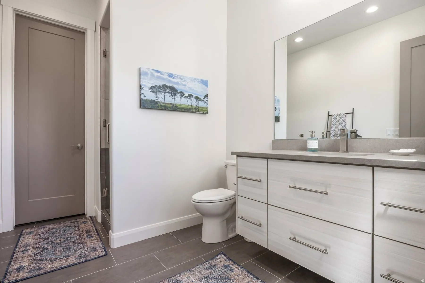Floating double vanity with integrated sink, rectangular mirror, recessed lighting, and tile flooring