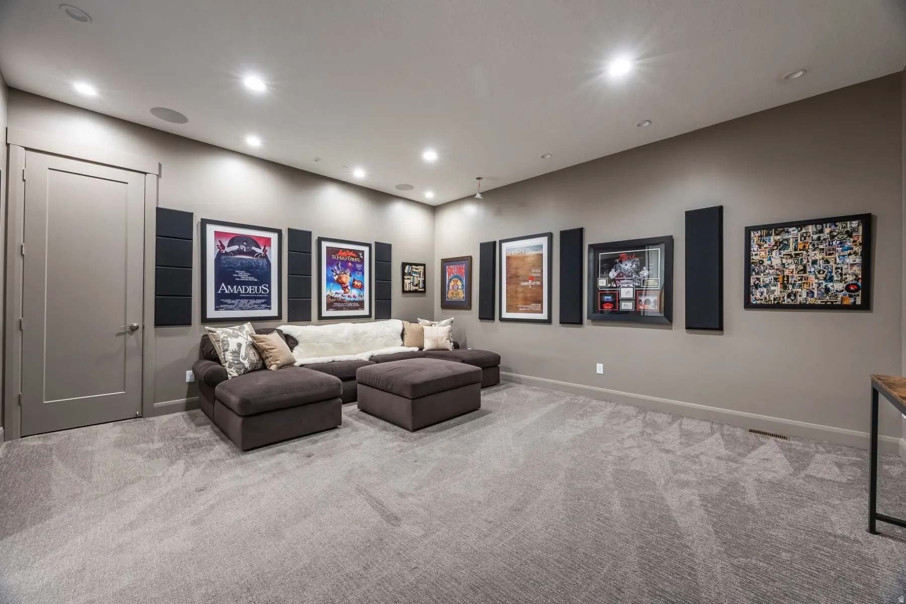 Recessed lighting, acoustic wall panels, neutral wall color, built-in sound system, and gray patterned carpeting