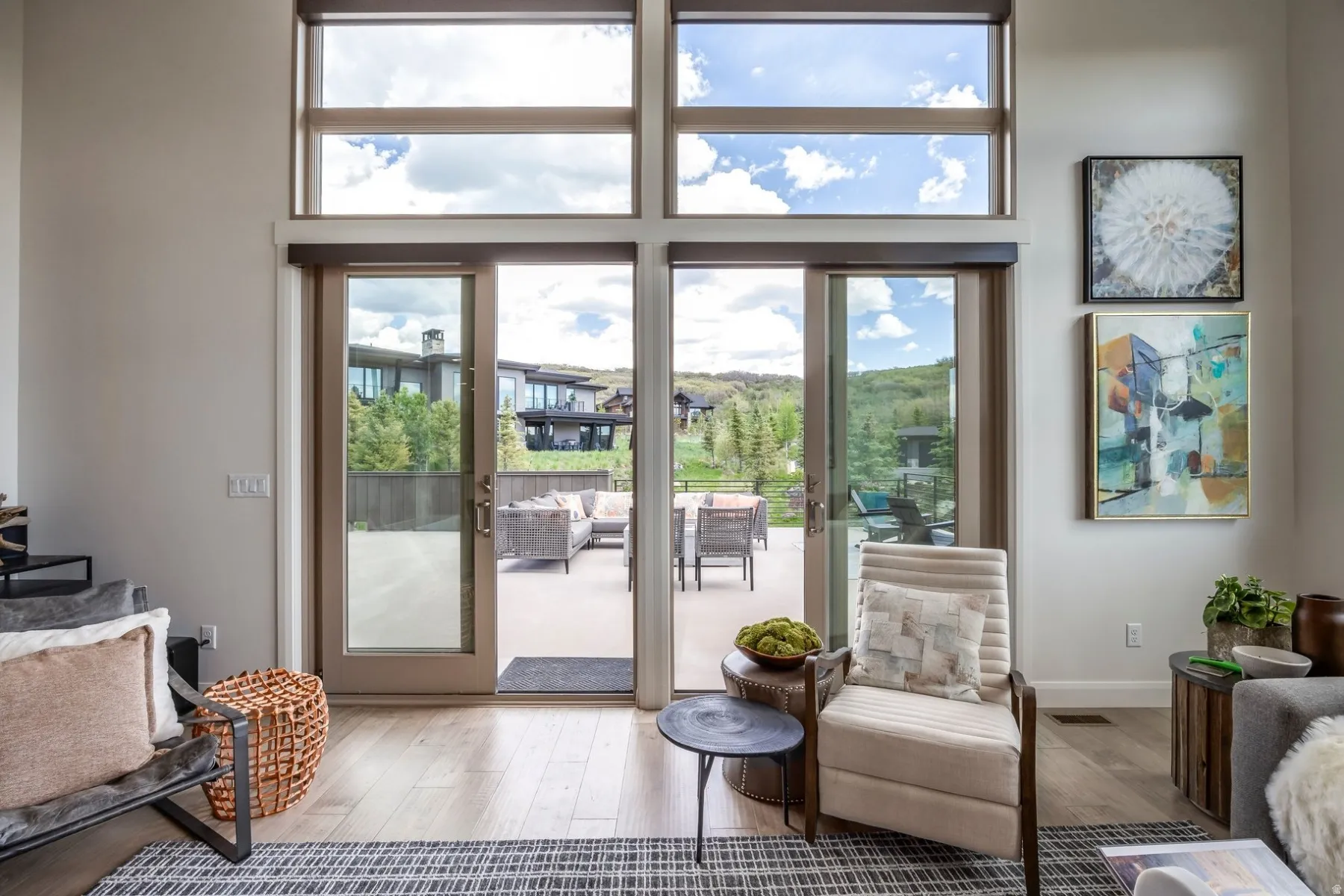 Sliding glass door access to an outdoor patio with wood-finish flooring and upper transom windows