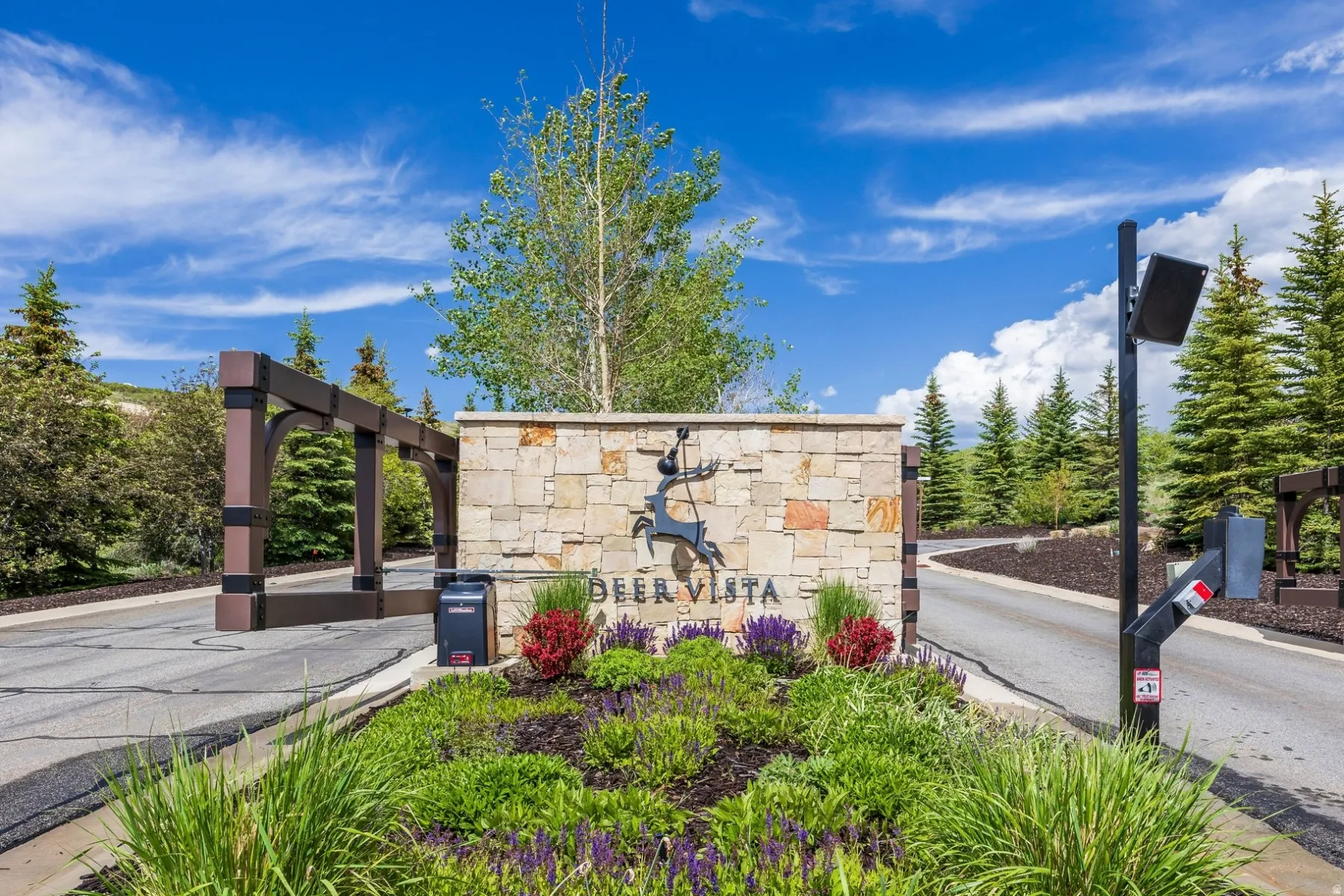 Stone-clad entrance monument with integrated signage and decorative metalwork