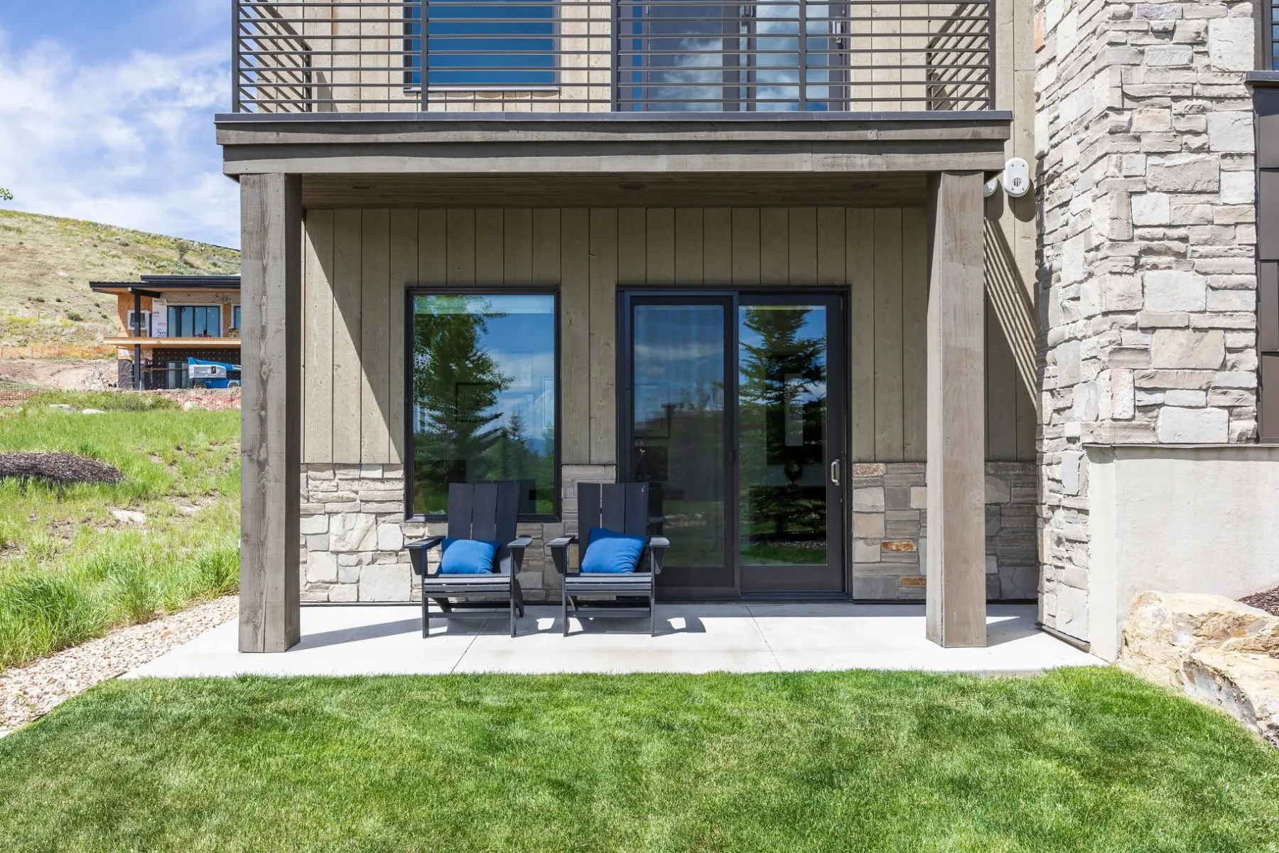 Ground-level patio with sliding glass door access, featuring a stone and wood-paneled exterior