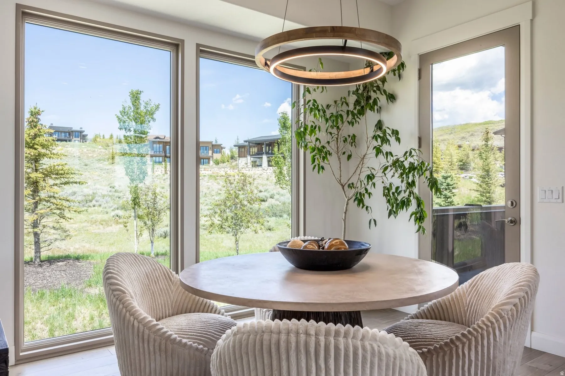 Spacious dining area featuring large windows, a glass-paneled exterior door, and a modern circular chandelier