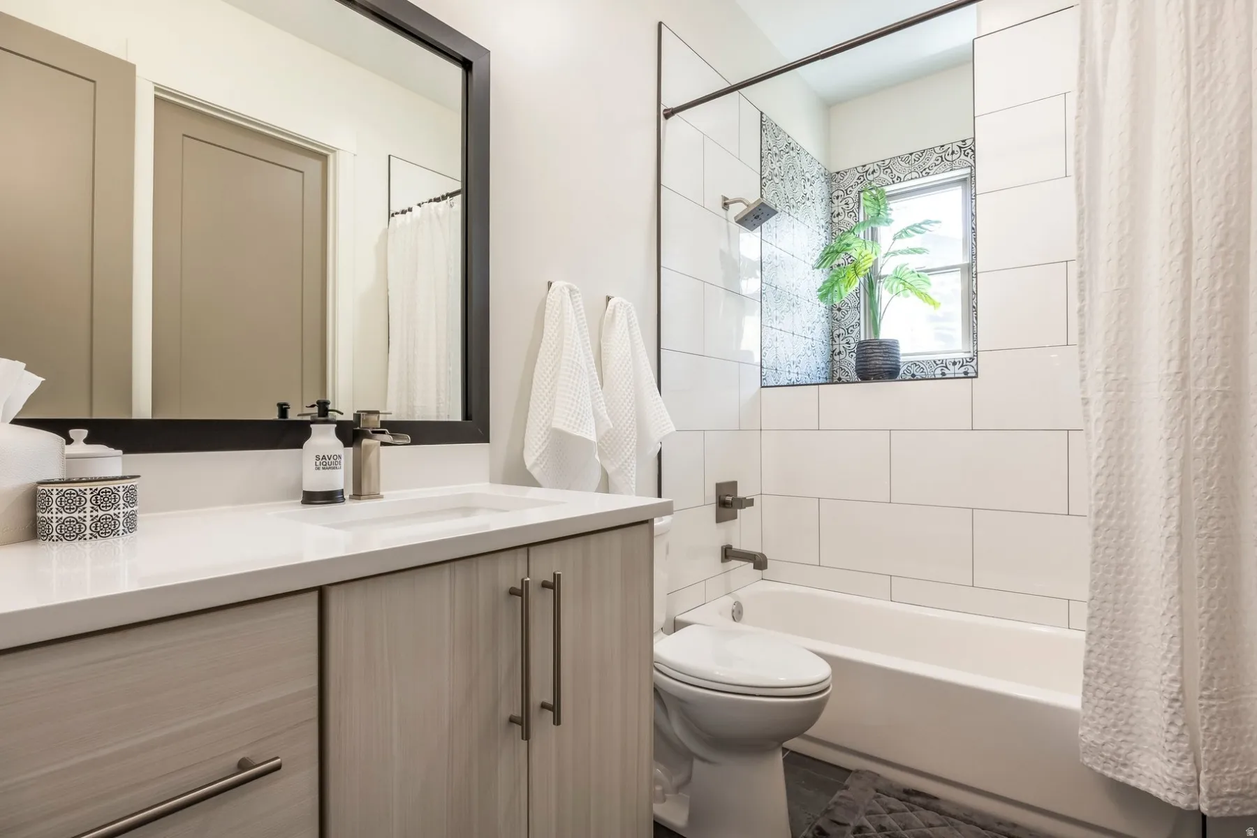 White subway tile shower surround with a patterned accent wall