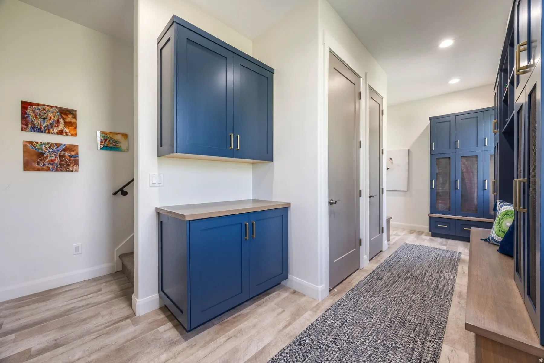 Integrated cabinetry, wood-finish flooring, recessed lighting, built-in storage, and a bench