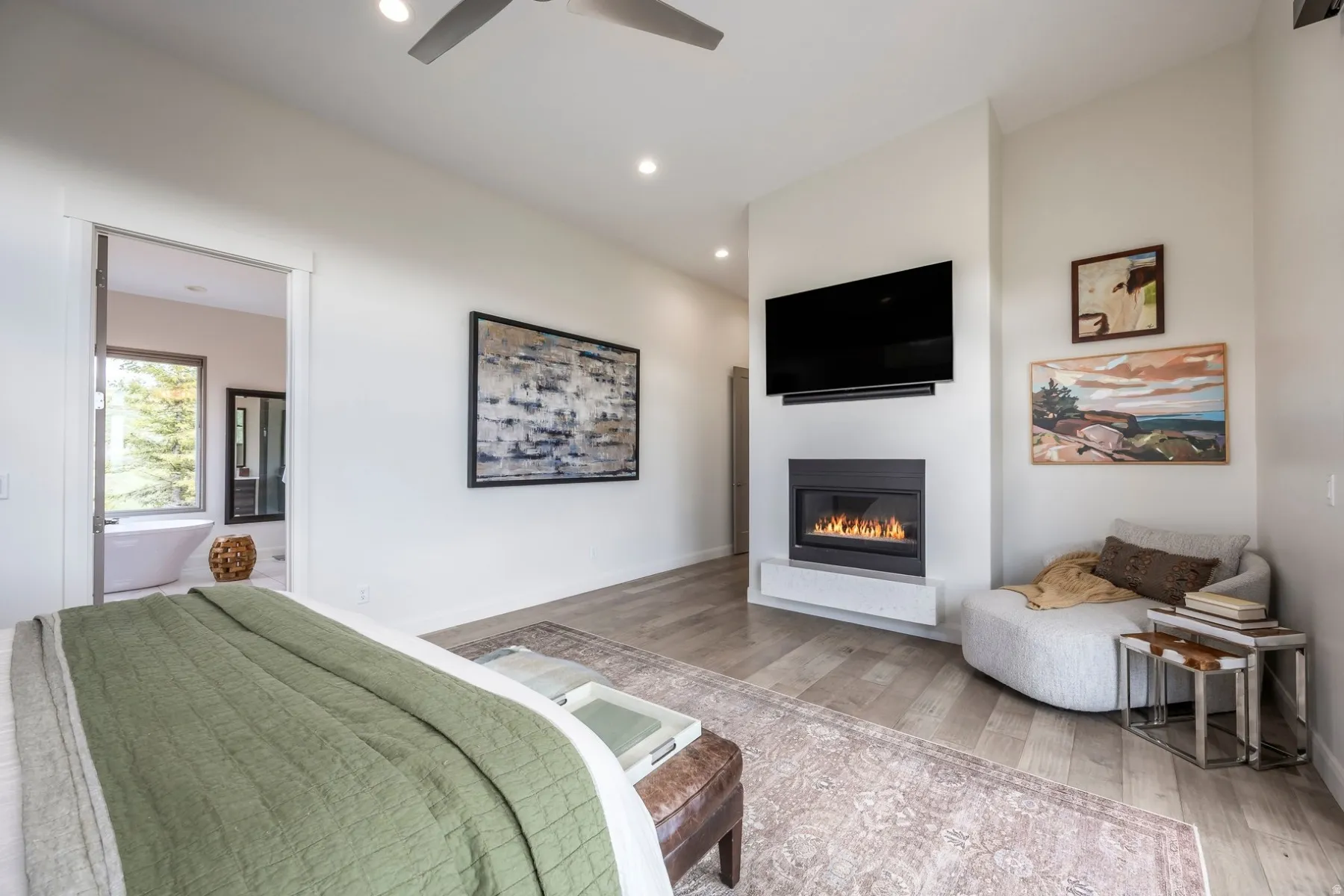Recessed lighting, wood-finish flooring, and a modern fireplace with a white hearth
