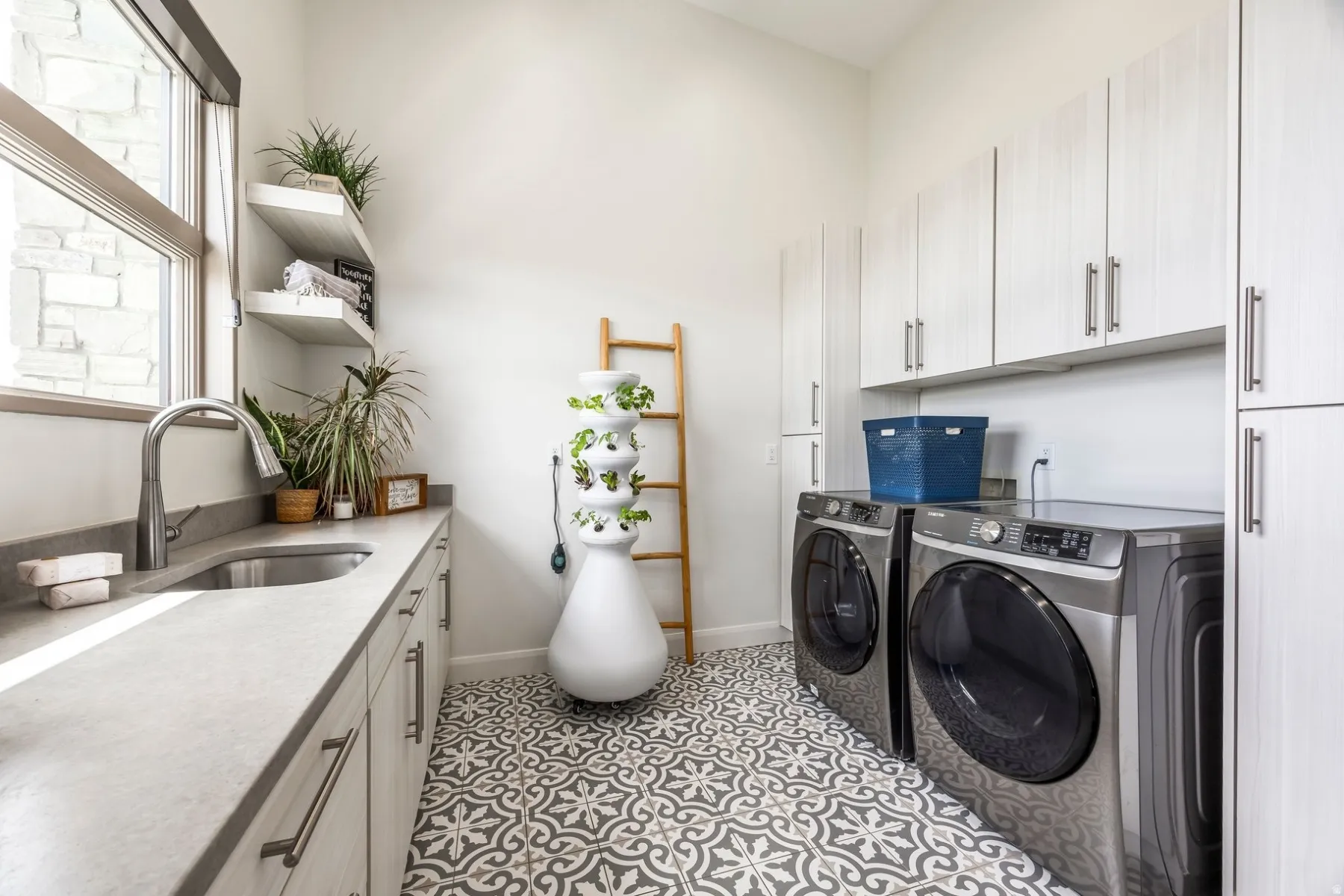 Window with stone exterior element, custom floating shelves, built-in cabinetry, under-mount sink, and patterned floor tile