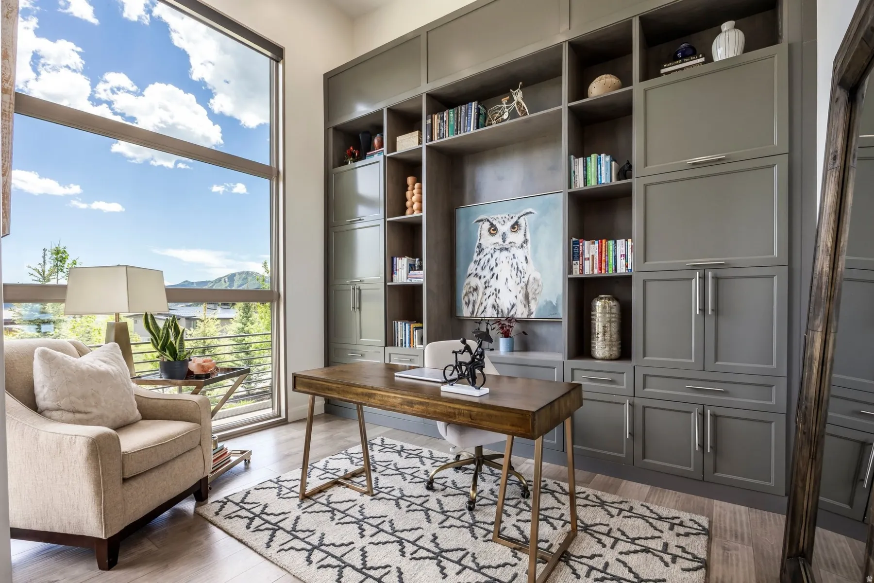 Floor-to-ceiling window, built-in cabinetry with open shelving, wood-finish flooring, and a substantial desk