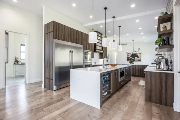 Gourmet kitchen featuring a large central island with integrated wine cooler, stainless steel appliances, wood-finish cabinetry, and recessed lighting