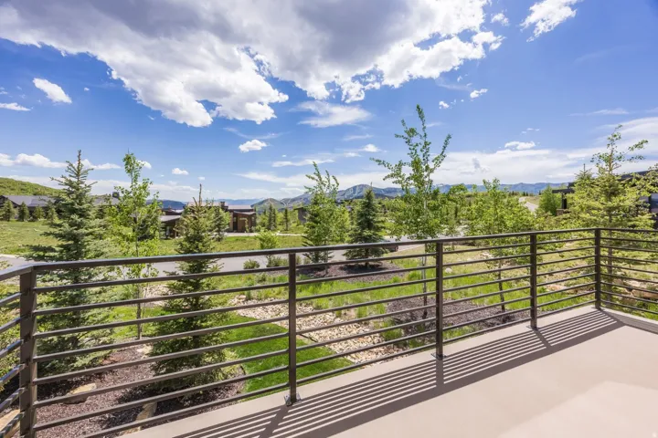 Outdoor balcony featuring a metal horizontal railing, a paved surface, and a mountain backdrop