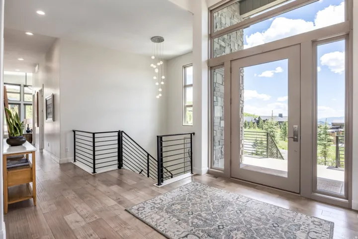 Entry with wood-finish flooring, a modern chandelier, and a metal horizontal bar railing