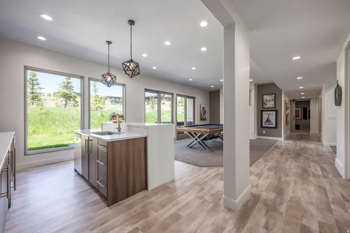 Wood-finish flooring throughout, recessed lighting, and a wet bar with a stainless steel sink