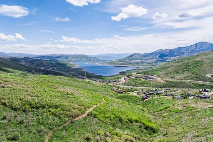 Expansive mountain landscape featuring a large body of water, green hillsides, and distant residences