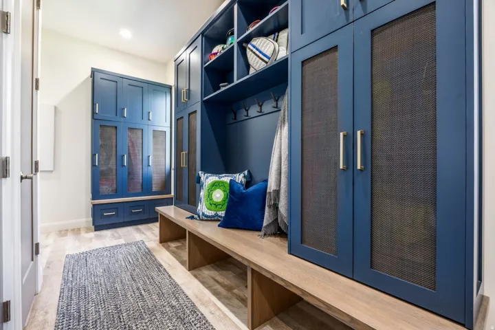 Built-in navy cabinetry with mesh-front doors, open shelving, and a wood-finish bench
