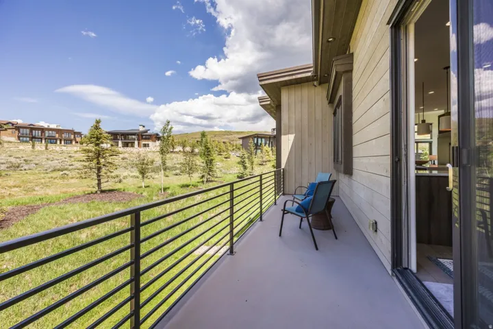Expansive outdoor patio with metal railing, sliding glass door, and wooden exterior siding