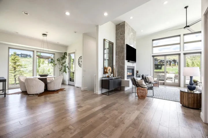 Wood-finish flooring, recessed lighting, and a stone-clad fireplace with a hearth