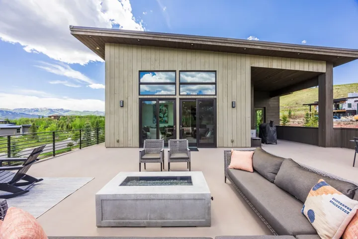 Expansive outdoor deck with a concrete fire pit, large sliding glass doors, and a covered patio area
