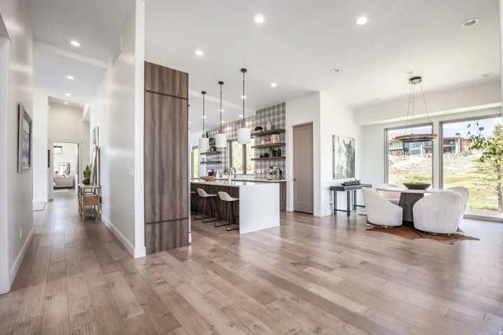 Open-concept living space with light wood-finish flooring, recessed lighting, expansive windows, a kitchen island, and a dining area