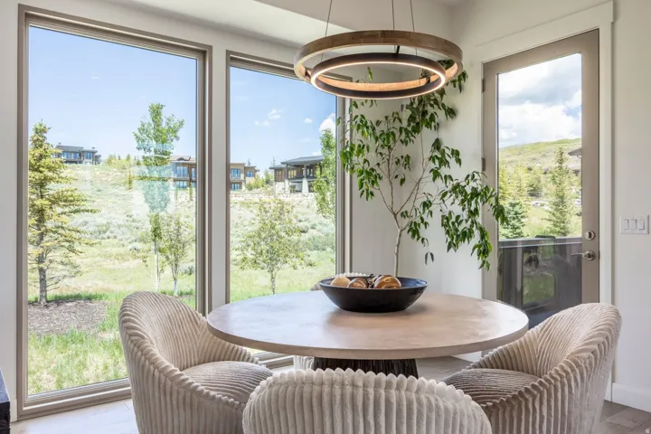 Spacious dining area featuring large windows, a glass-paneled exterior door, and a modern circular chandelier