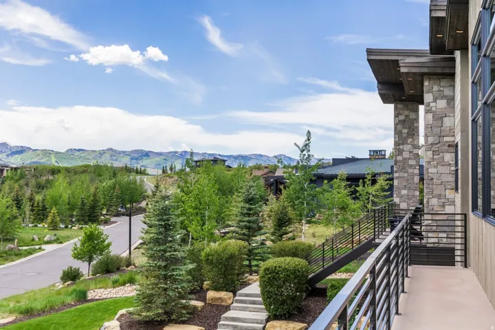 Stone and wood-clad exterior with expansive windows, a concrete balcony, and horizontal metal railings