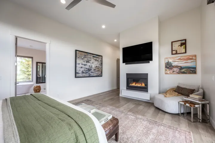 Recessed lighting, wood-finish flooring, and a modern fireplace with a white hearth