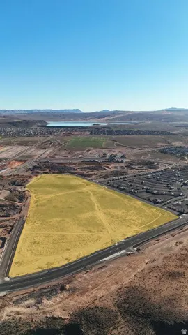 Expansive land parcel with surrounding developed areas, offering clear sky visibility and distant water body