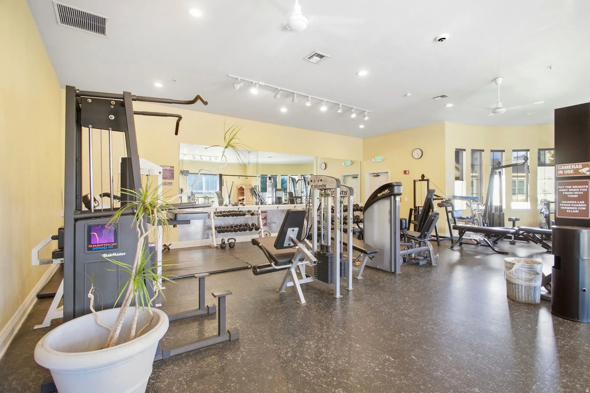 Fitness center featuring recessed lighting, track lighting, ceiling fans, and a mirrored wall