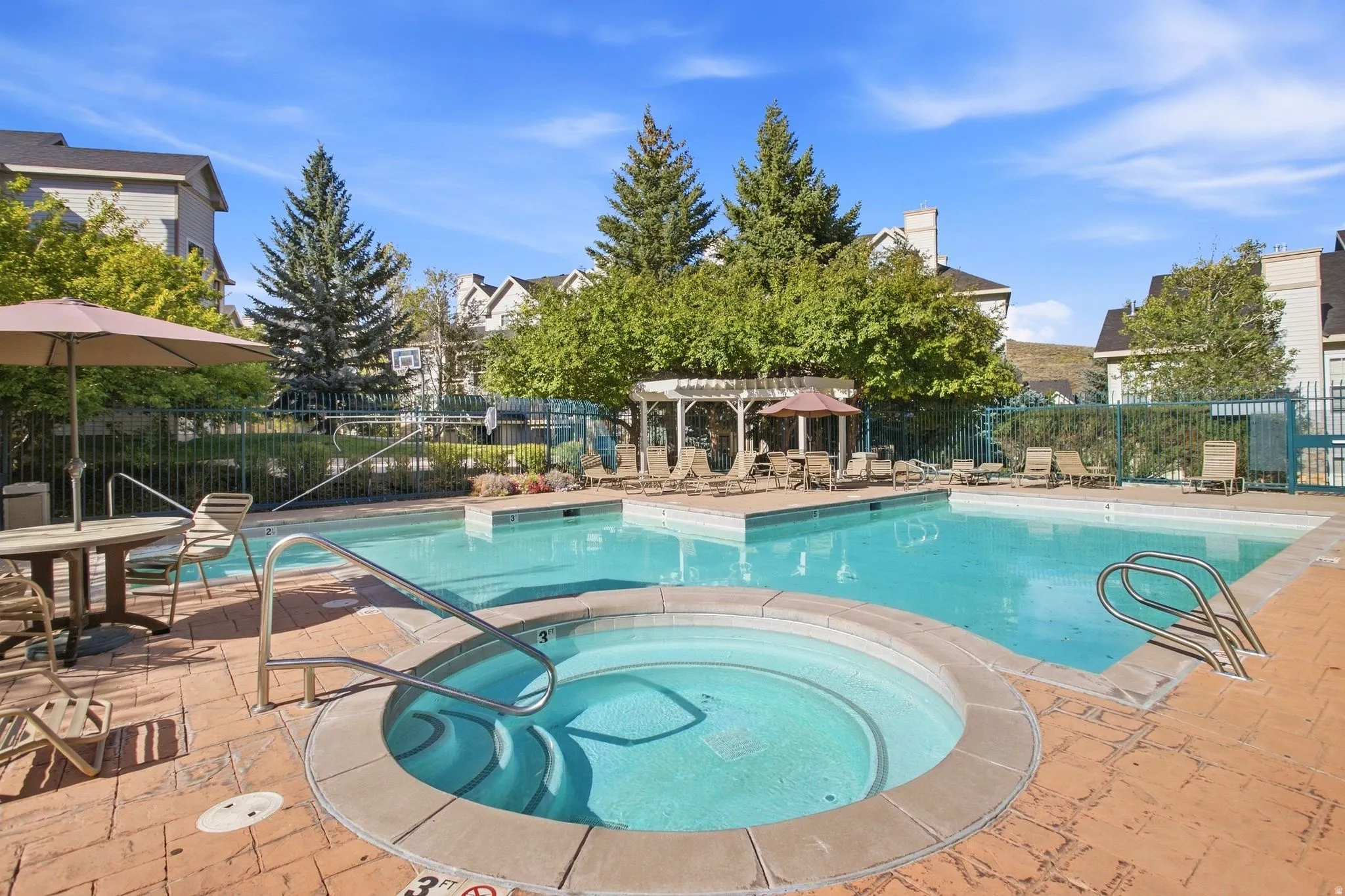 Swimming pool area featuring a hot tub, brick paver decking, and a shaded pergola