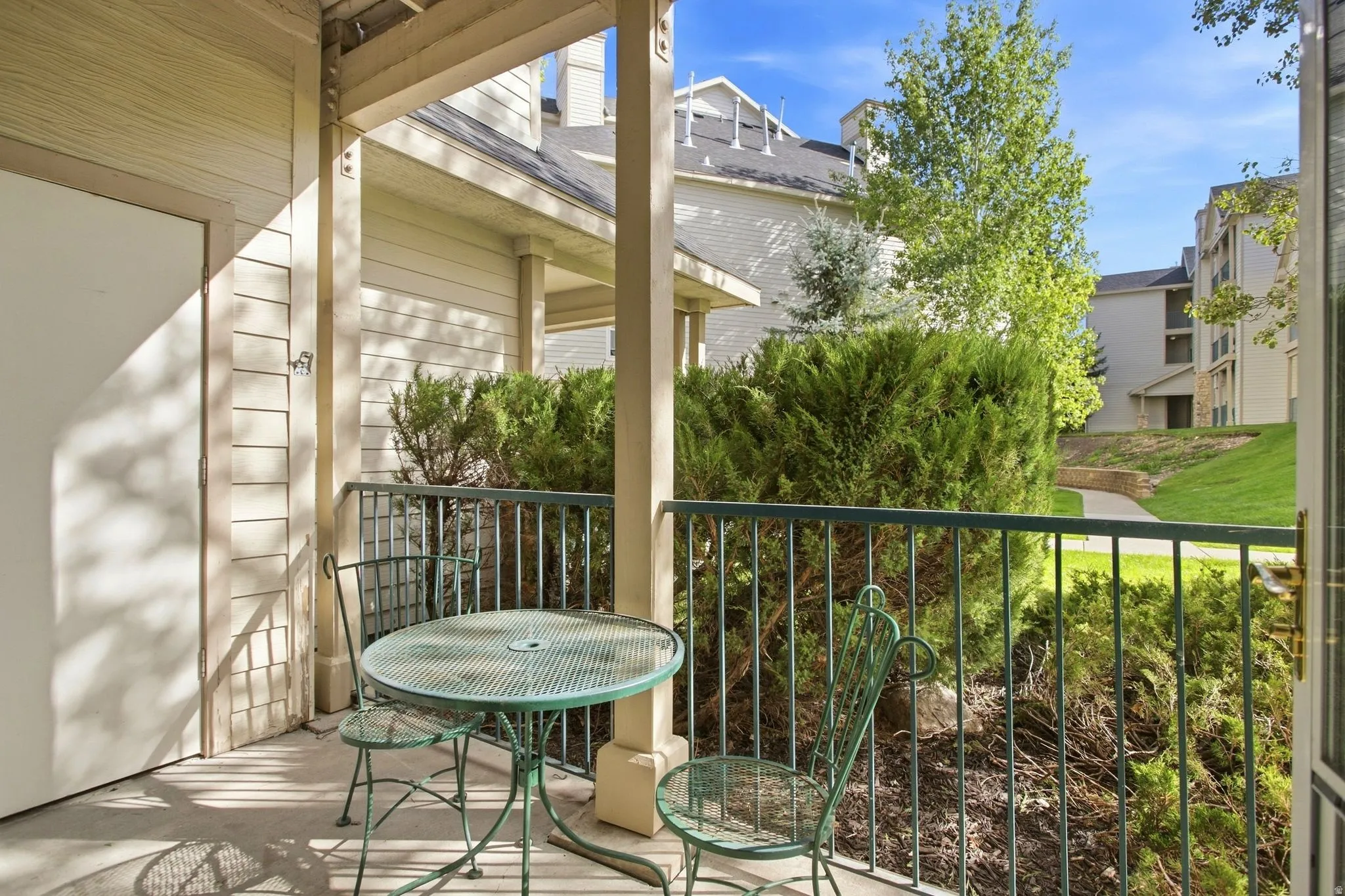 Private patio featuring a concrete surface, painted wood siding, and an iron railing