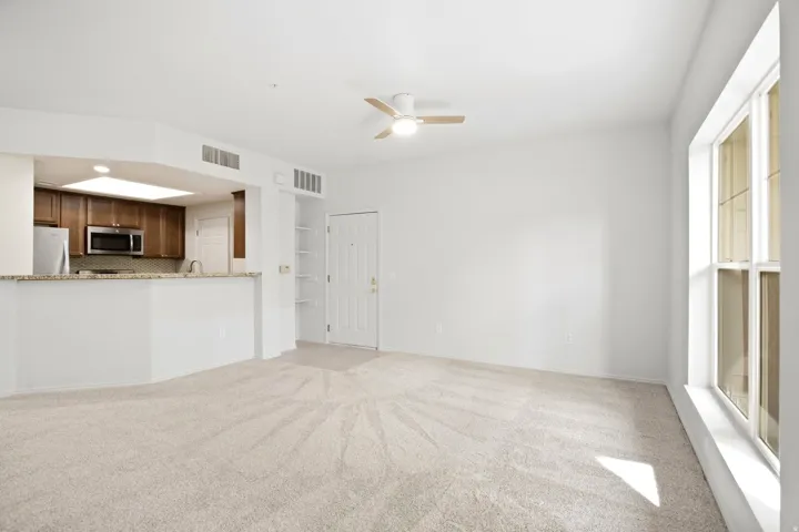 Living area with light-toned carpeting, a ceiling fan, and a large window