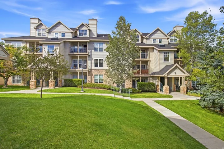 Multi-story building featuring balconies, gabled rooflines, stone facade accents, and a covered entry