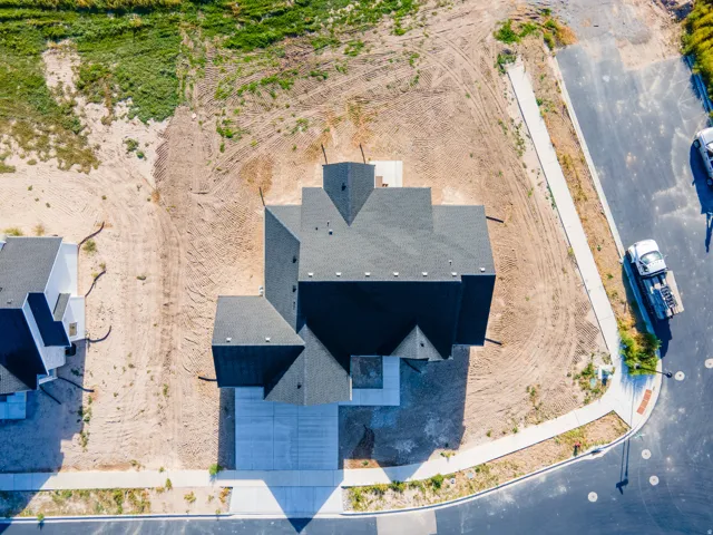 Newly constructed home with dark shingle roofing, an attached garage, and a concrete driveway