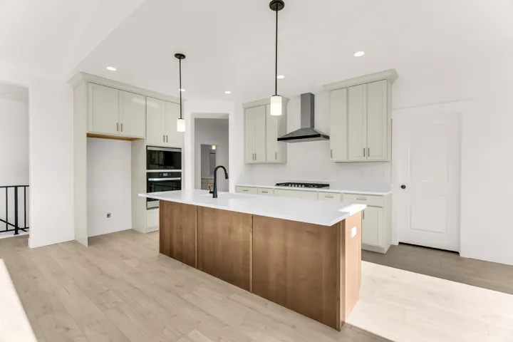 Kitchen featuring a large wood-finish island with a white countertop, two pendant lights, and a black faucet