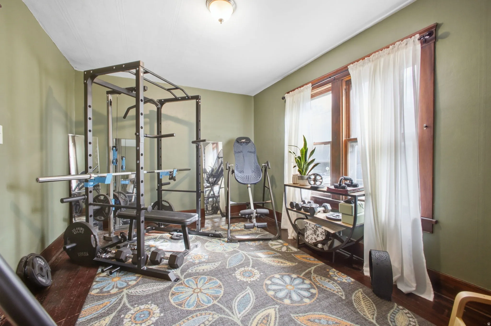 Exercise or bedroom featuring hardwood flooring, warmly painted walls, and original wood trim.