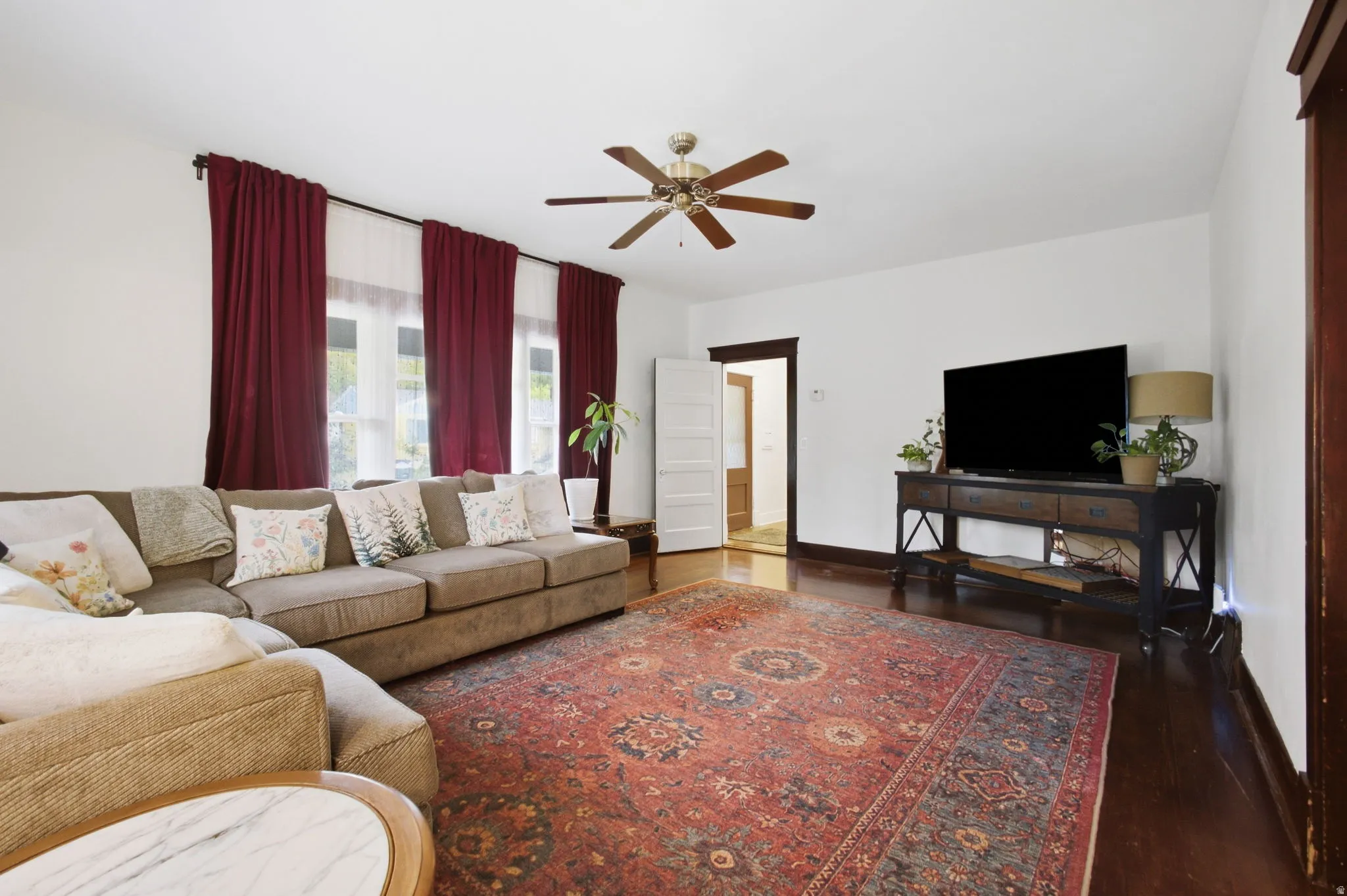 Hardwood flooring, painted white walls, ceiling fan, and multiple windows for natural light.