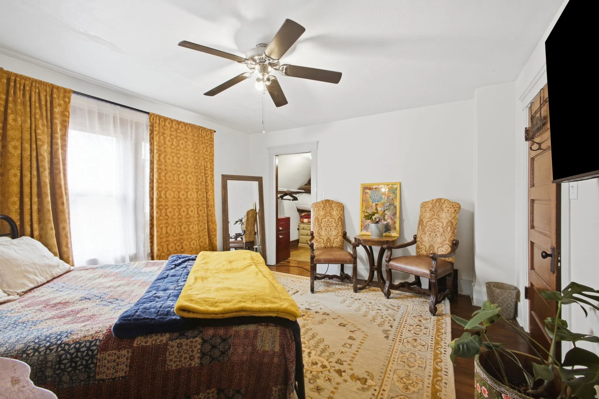Ceiling fan fixture, wood-finish flooring, white painted walls, window with natural light and walk in closet.