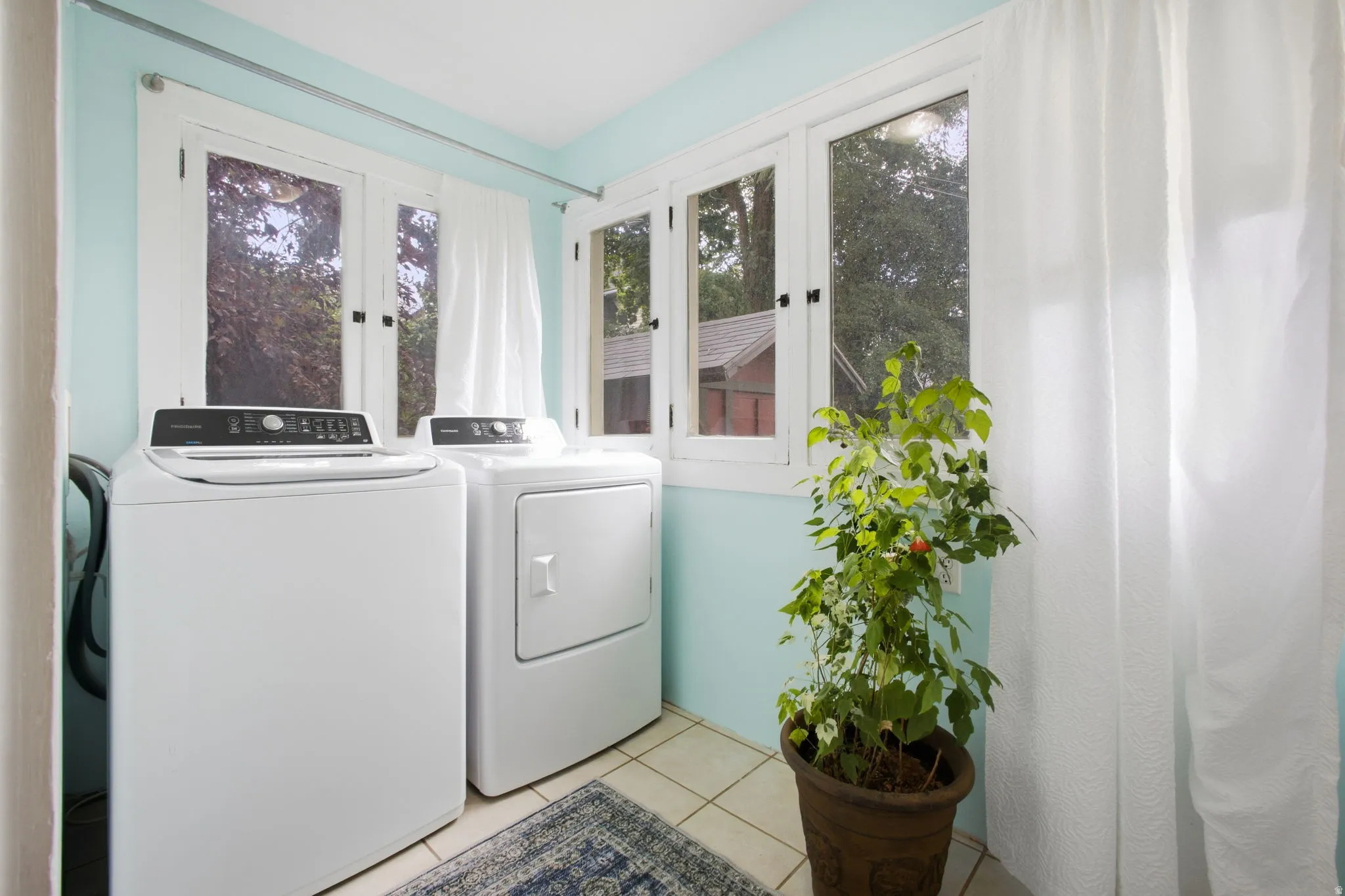 Large format white tile flooring, multiple windows with white trim, teal wall finish with original cabinets.