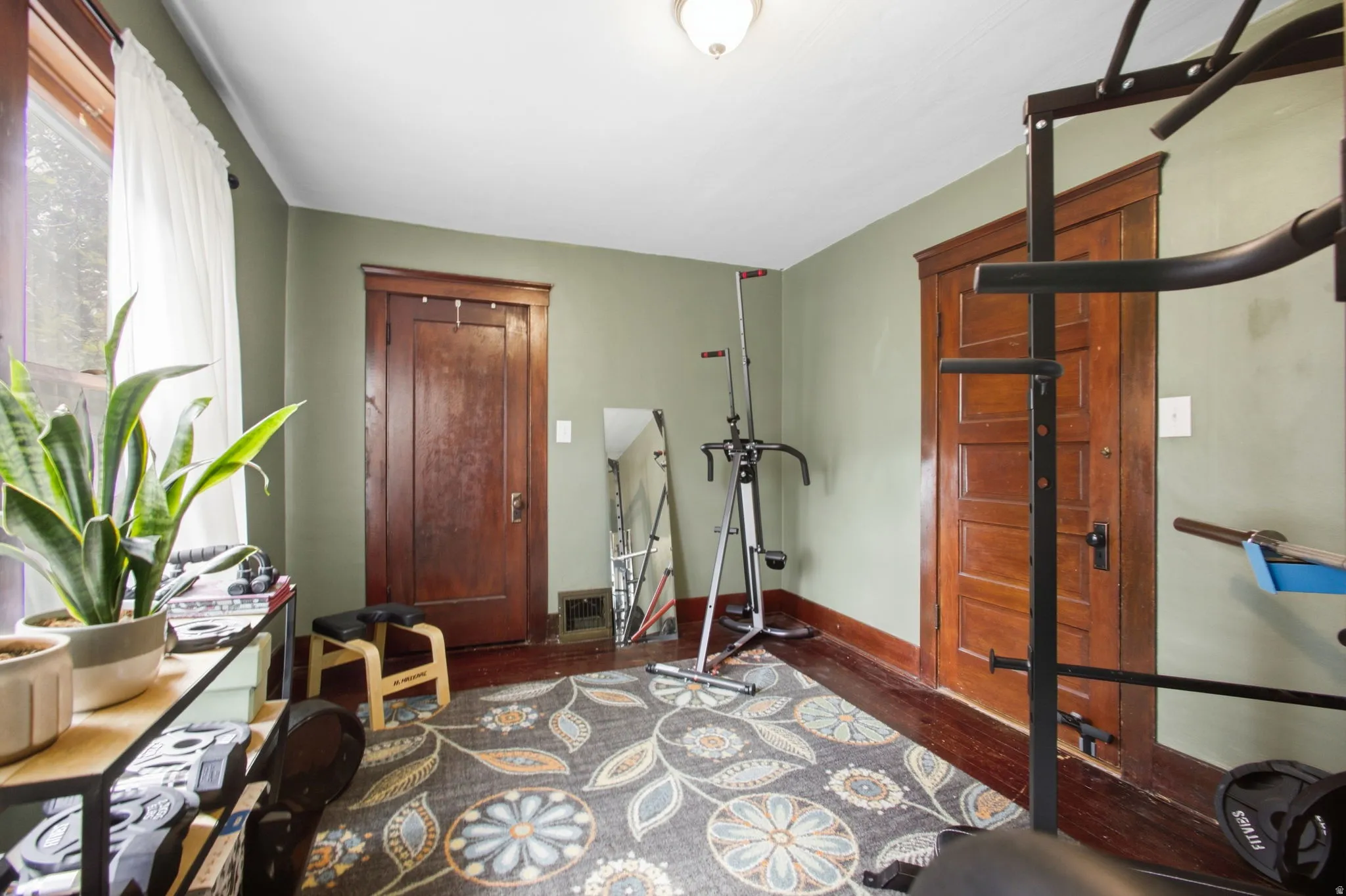 Room with two wood-finish panel doors, wood-finish flooring, and window for natural light.