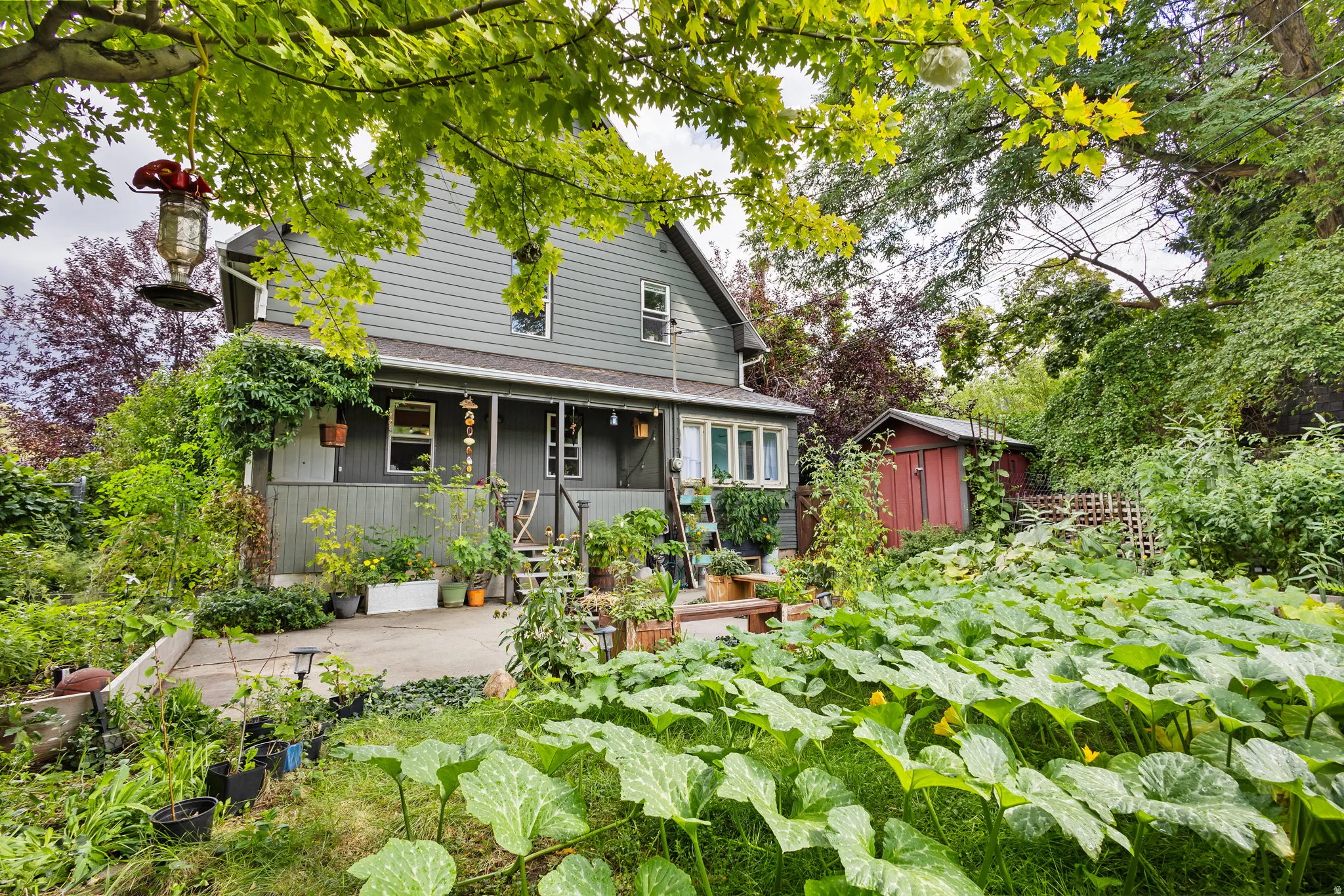 Newly painted siding exterior with a covered porch, an expansive garden area, and an accessory storage shed.