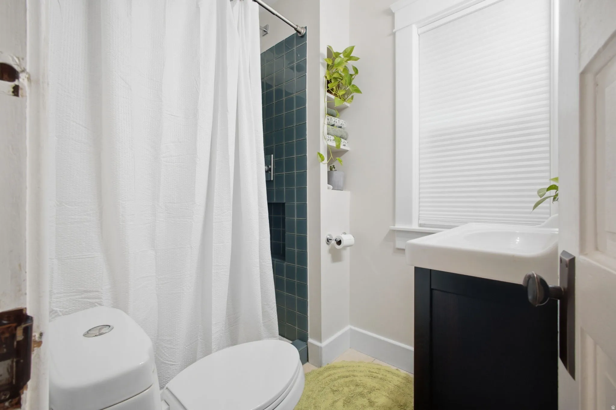 Bathroom featuring a large dark tiled shower and updated vanity.